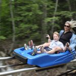 A woman and a young child ride along Berkshire East's mountain coaster on a summer day.