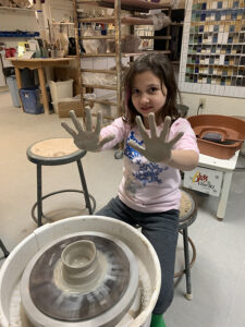 Girl at IS183's pottery wheel
