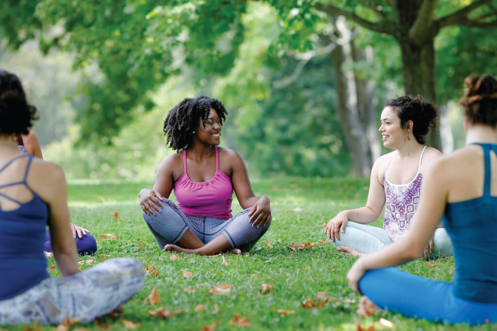 31 group outdoors (1) A group of women sit in a circle at an outdoor fitness class in summer