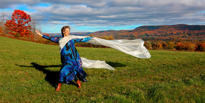 Woman dances in open field outdoors among fall foliage
