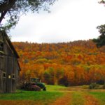 Fall foliage surrounds a farm land with a barn and tractor