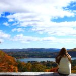 Woman sits along ledge at Olivia Overlook admiring the fall foliage