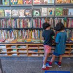 Two young children look at books in the large display at the Eric Carle Museum