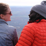 A couple looks at each other while embracing on a picturesque view of the Berkshire mountains.