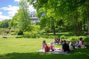 A large group spreads out on the lawn of The Mount to enjoy a picnic in the spring
