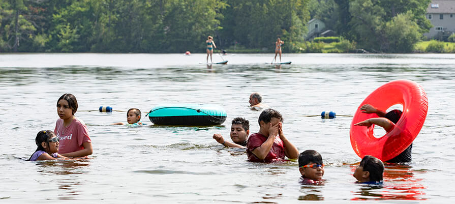 A group of children enjoy swimming in a lake during summer.