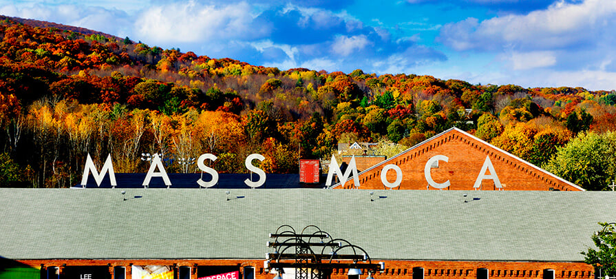 MASS MoCA sign above the museum surrounded by colorful fall foliage backdrop