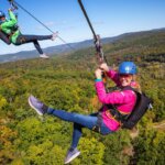 Two women smiling as they zipline above the trees at Catamount Mountain Resort