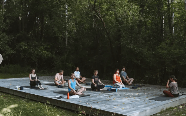 A group of people in yoga poses on an outdoor platform