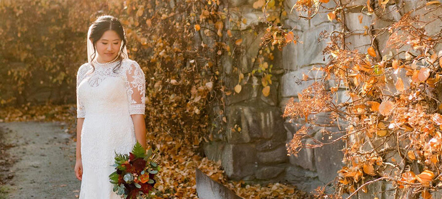 Bride stands in front of autumn foliage
