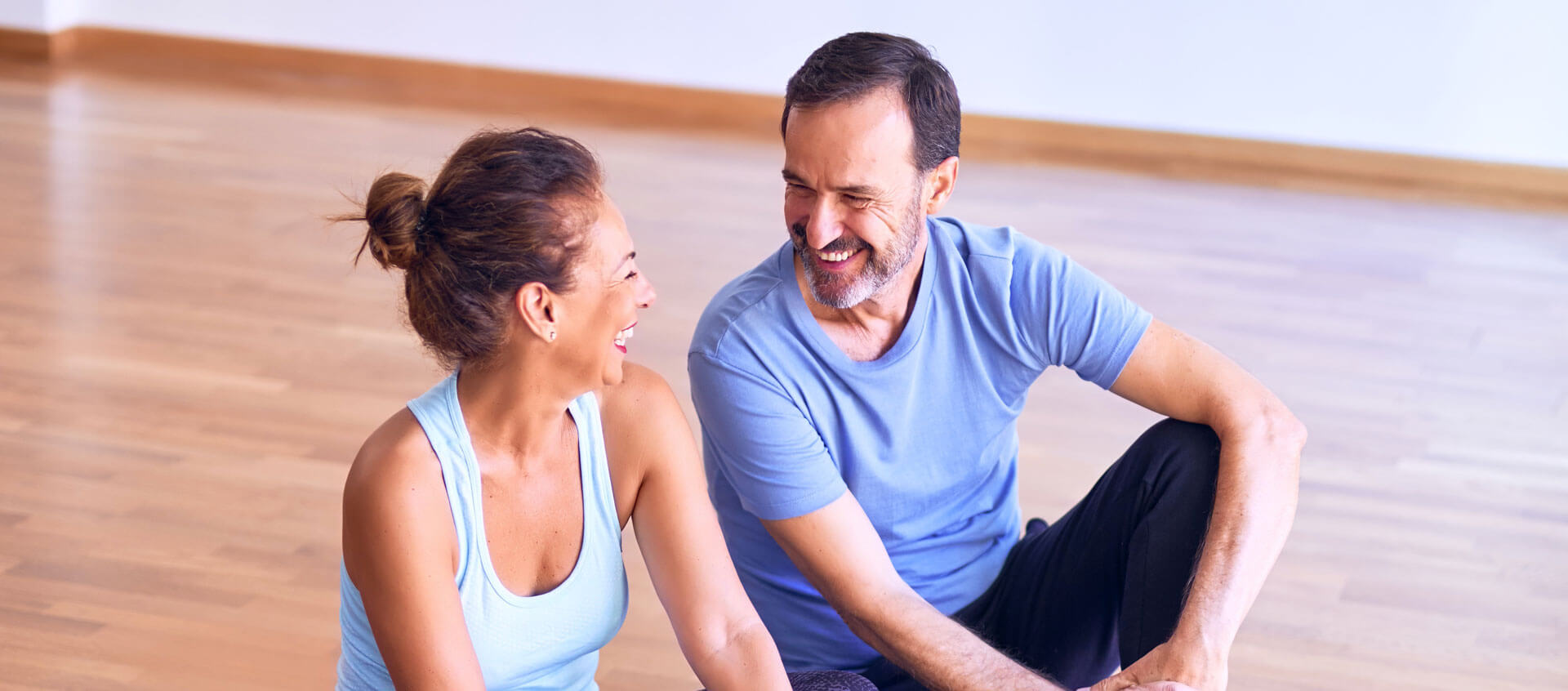 a couple seated on the floor of a yoga studio enjoying conversation
