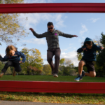 A father and children jumping through an art exhibit at Norman Rockwell Museum in the Berkshires.