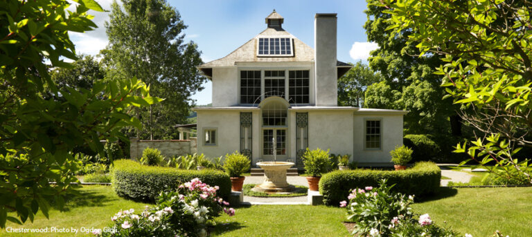 Chesterwood Studio is a white stone house with many glass windows. A fountain is in front in a green and flowery garden and lawn.