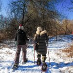 Two people enjoy a showshoe hike on a sunny day