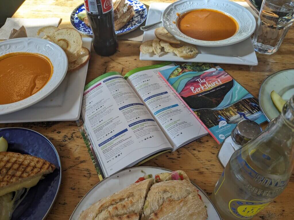 Table filled with sandwiches and soups for lunch, surrounding the Official Guide to the Berkshires book