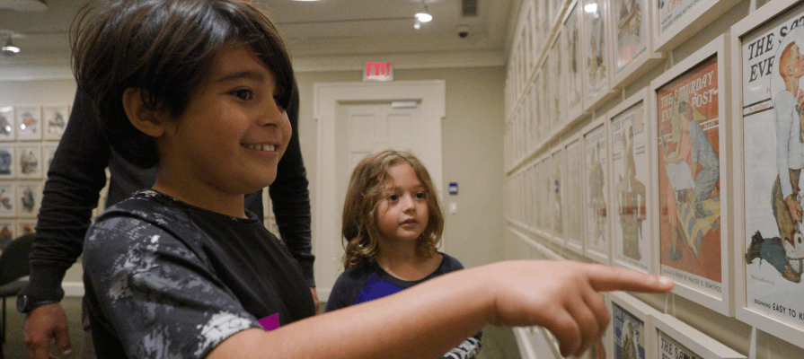 Two children admire artwork hung on the wall at the Norman Rockwell Museum. 