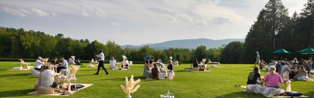 People sit on picnic blankets spread across the green grass at Tanglewood on a sunny day
