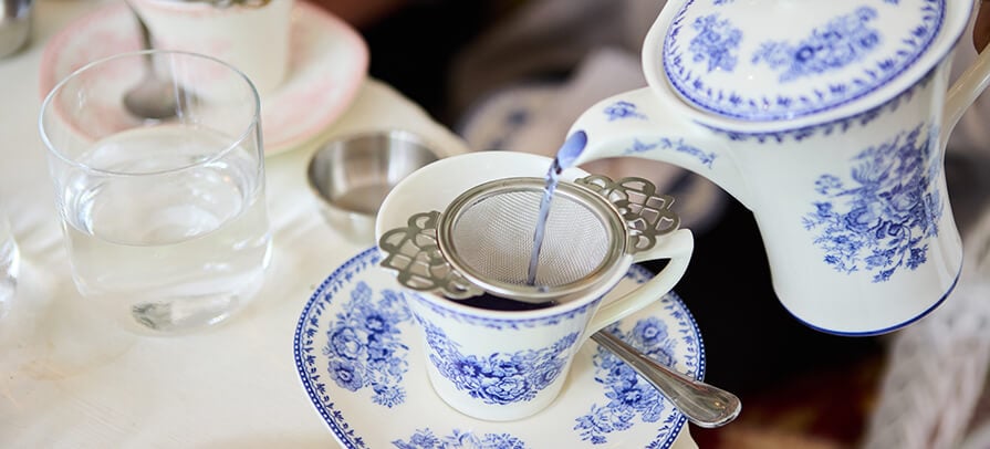 A delicate blue and white tea pot pours a blue tea into a matching cup and saucer during afternoon tea service at the Red Lion Inn