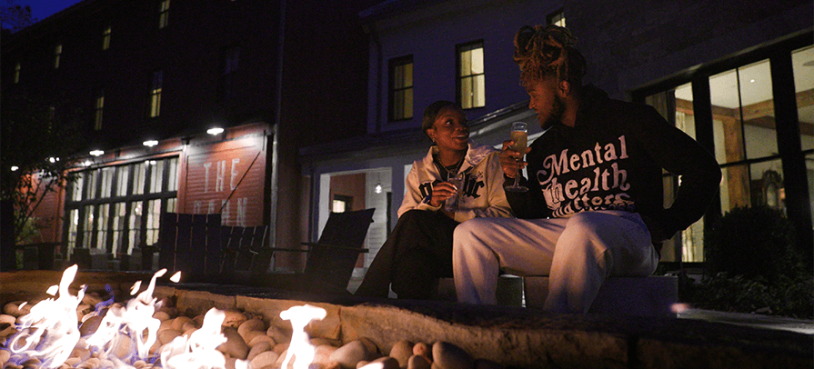 A couple sits fireside at the Williams Inn with glasses of wine