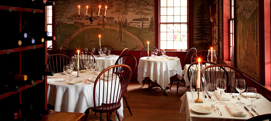 The classic diningroom at the Old in on the Green is pictured with lit candles and fine dining elements.