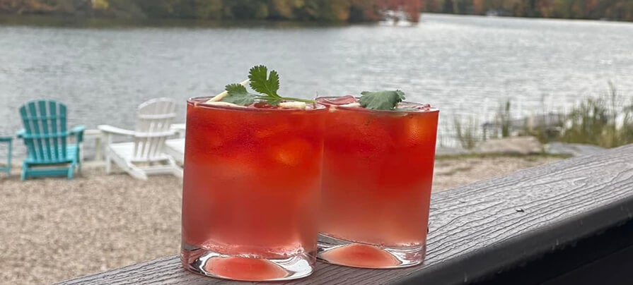 Two red cocktails sit on the porch at Mint Indian Lakeside Dining