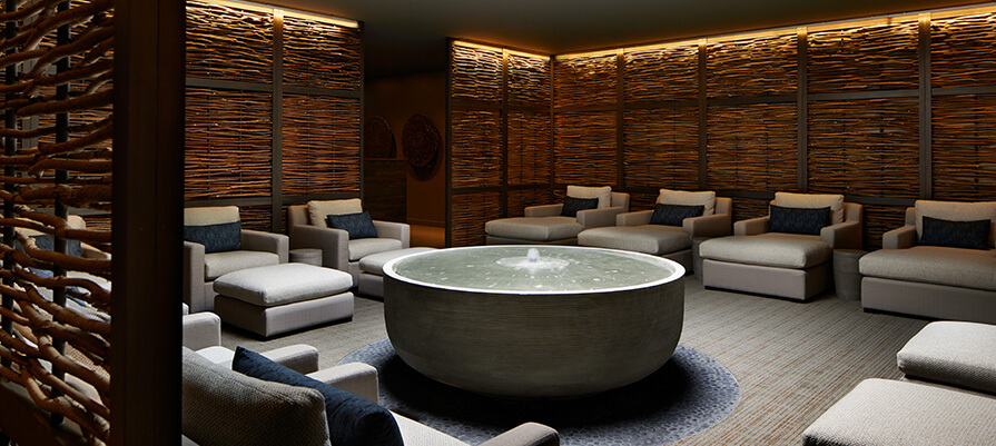 The tranquil room has soft large lounger chairs all around a water feature in a quiet relaxation lounge at Miraval