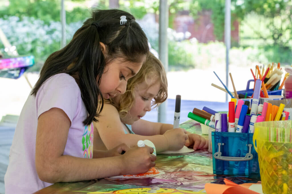Two young children participate in coloring and crafts outdoors during ArtWeek Berkshires.