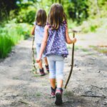 Two young girls walking along a trail in the summer