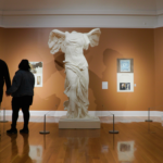 A couple stands holding hands while looking at sculptures in the Berkshire Museum