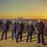 Band members of Los Lobos in front of a sunset