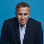 headshot of actor Paul Reiser against a blue background