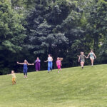 Family ehjoying time together outside, running down a hill