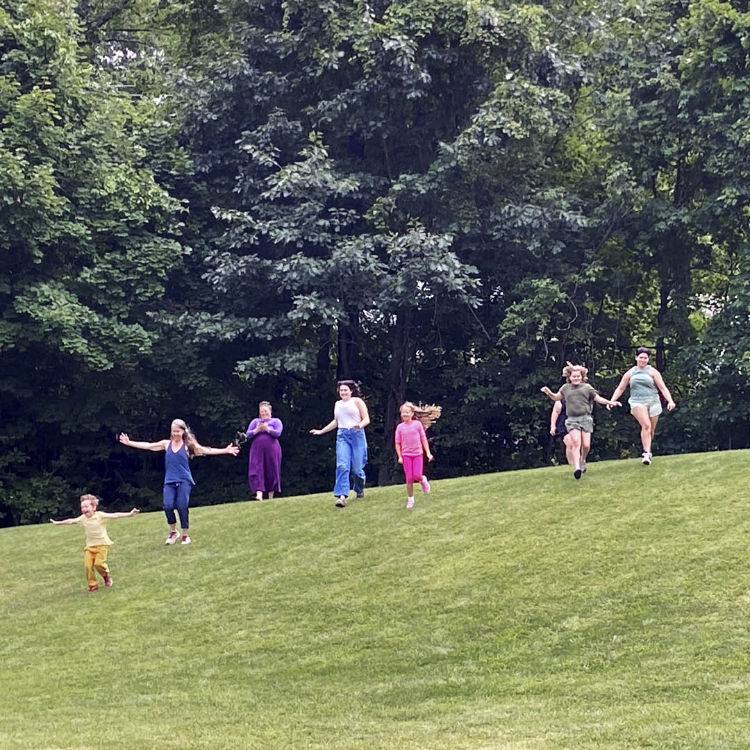 Family ehjoying time together outside, running down a hill