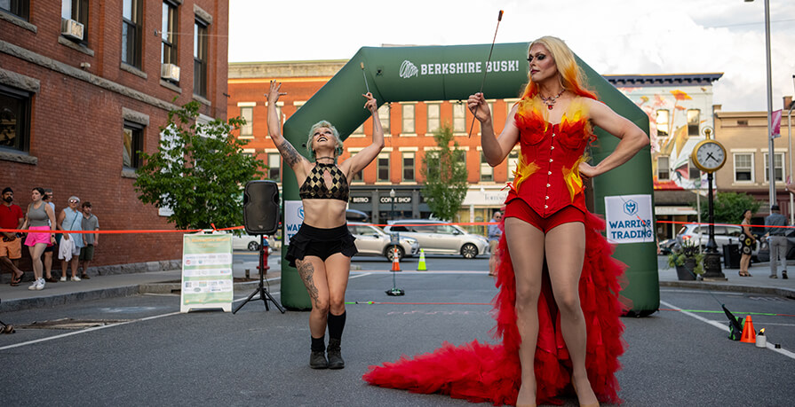 Two performers hold fire sticks and dance at Berkshire Busk!