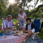 A family of three sits on the lawn at Tanglewood in summer enjoying a fancy picnic