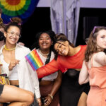 pillow-pride-25-895×400 A group of young adults pose while celebrating at Jacob's Pillow Pride, with Pride flags and accessories.