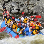 A group of rafters stick their paddles out on the white water rafting guide from the Deerfield River.