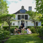 A small group clicks glasses in cheers while sitting at a picnic at Chesterwood.