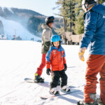 A child and two adults coast on the snowy mountain of Berkshire East while snowboarding