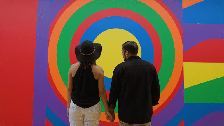 A couple stands in front of art at MASS MoCA holding hands