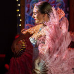 A woman dances in a stage light with pink costume.