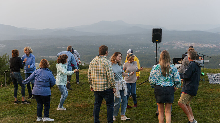 A group of people sing and dance to live music on Bousquet Mountain