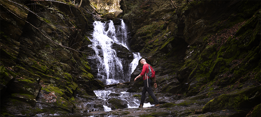 A man hikes along a waterfall in spring. 